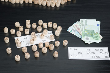 Wooden barrels lotto, cards and euro. Black wooden table.