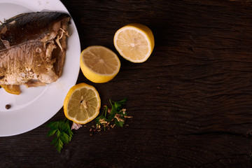 Grilled fish with herbs and lemon on wooden background. Mediterranean luxurious seafood concept