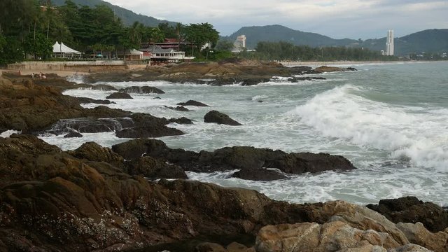 sea wave hit the rock shore seascape , Patong sand beach Phuket  parasail , tree and mountain are  background ,