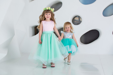  Beautiful children in dresses in a white room. Girls play and laugh