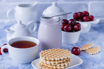 Breakfast. White cup of tea with thin waffles, lemon jam, yogurt and fresh fruit.