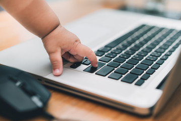Finger hand of baby typing keyboard on laptop computer in office home learning startup to little businessman.