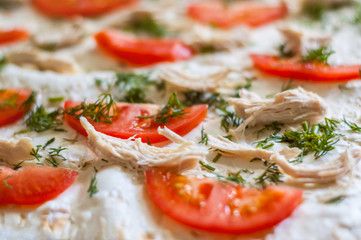 Pizza ingredients are closeup. Tomatoes, chicken, cheese, dill. Blurred background