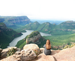 Woman with long brown hair sitting on the edge of Blyde River Canyon in South Africa