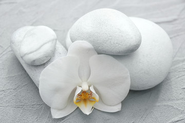 Obraz na płótnie Canvas Spa stones and beautiful orchid flower on grey textured background
