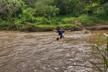 Young man crossing the river on zip line in Chiang Mai Thailand