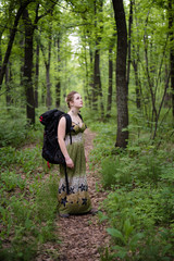 girl tourist with a backpack traveling in the forest