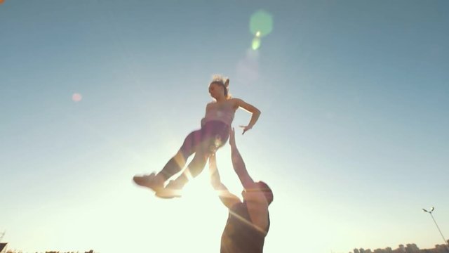 Team of cheerleaders workout outdoors at summer day - muscular man throws the girl performing flip in the air