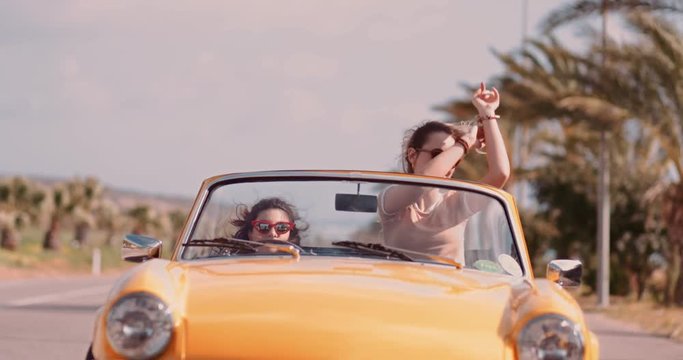 Best friends having fun driving convertible on exotic summer holidays
