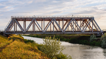 Fototapeta na wymiar Old metal railway bridge through the water channel