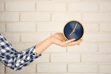 Woman holding clock near brick wall. Time management concept