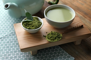 Fresh matcha tea and bowl with powder on wooden stand