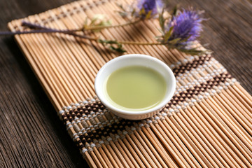 Bowl of fresh matcha tea on bamboo mat
