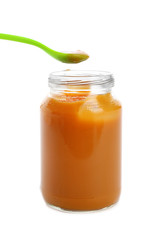 Jar and spoon with healthy baby food on white background