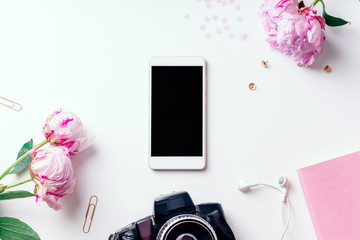 Feminine workspace with pink peons and phone mock up on white background with copy space