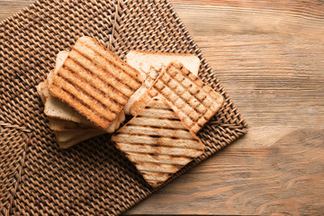 Tasty toasted bread on wicker mat