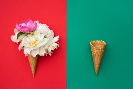 Two waffle ice cream cones with peony flowers on red green background. Summer concept. Copy space, top view