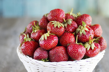 Whole red strawberry in white basket  on  gray background.