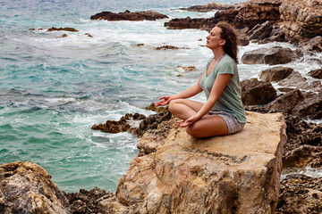 Fototapeta na wymiar Meditation by the sea. Woman in sunset doing yoga exercise