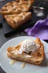 Plate with piece of tasty apple pie and ice-cream on table