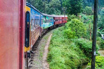 Naklejka premium NANU OYA, SRI LANKA - JULY 16, 2016: Local train rides through a rural landscape near Nanu Oya village, Sri Lanka
