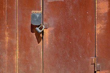 Segment of rusty garage doors with two locks.