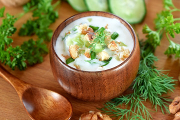 Cold soup Tarator with kefir in a wooden bowl. Bulgarian cuisine meal