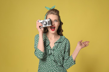 Beautiful young woman with photo camera on color background