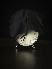 alarm clock on a dark background covered with a cloth.