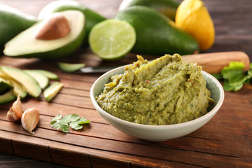 Bowl with delicious guacamole on wooden board