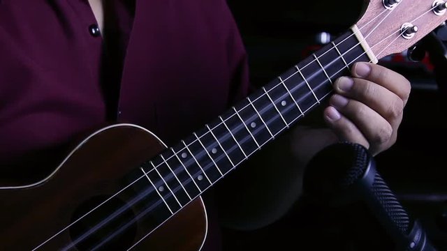 A man is playing ukulele in close up view, freeze motion and vibrant string