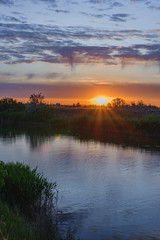 Fototapeta na wymiar Silence, sunset in the steppe, beautiful clouds and the water surface of the canal.