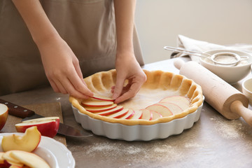 Woman preparing apple pie at table