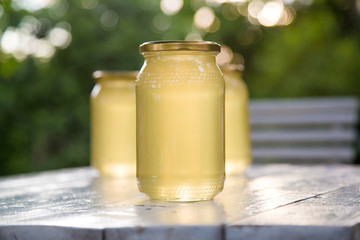 Glass of fresh liquid honey standing on rustic wooden table