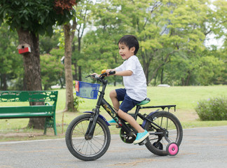 Fototapeta premium Asian cute boy ride a bicycle at park green nature background