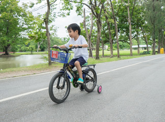 Asian cute boy ride a bicycle at park green nature background