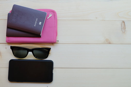 Travel concept: Top view and close up two passports, sunglasses, smartphone on wooden background (Flat lay style)