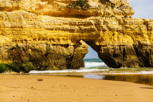 Algarve, Portugal, a stunning sea ocean landscape with yellow rocks and azure water.  Cabo da Roca, Portimao, the beauty of nature and the power of the ocean.  Sand reflection in the foreground. 