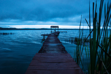 Pier with hut behind grass along the lake shore before sunset, El Remate, Peten, Guatemala
