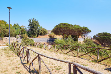 Fototapeta na wymiar Nice countryside landscape with wooden fence trees and clear blue sky in Pompeii, Italy