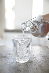 Close up pouring water to glass from the bottle on table in coffee shop