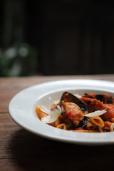 Penne pasta tomato sauce arabiata with seafood on wood background vintage style