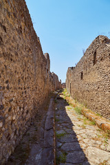 Fototapeta na wymiar Old historical walls with alley and clear blue sky in Pompeii, Italy