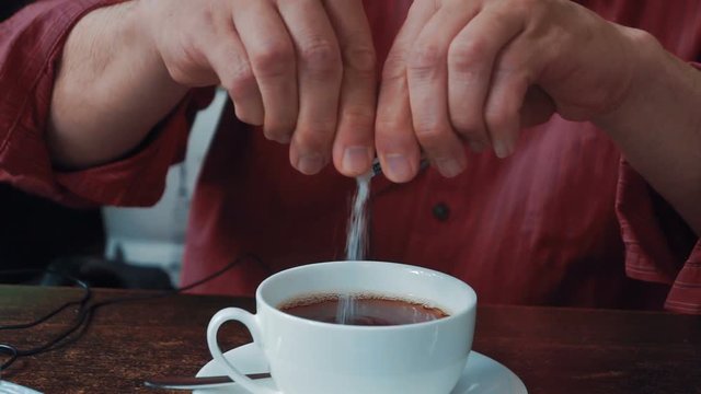Man Putting Sugar Into a Cup with tea.