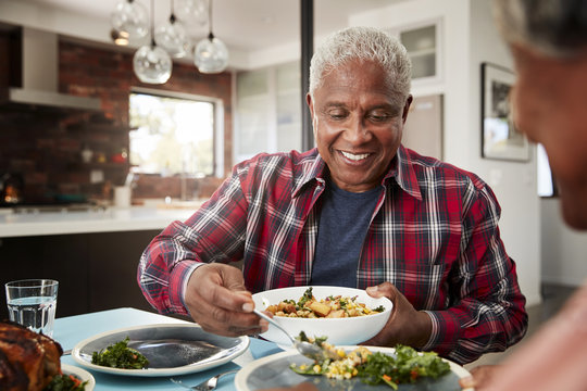 Senior Couple Enjoying Meal Around Table At Home - Powered by Adobe