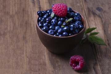full bowl of ripe forest blueberries on a dark background