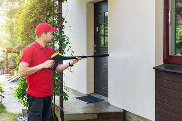 worker with high pressure washer cleaning house facade - obrazy, fototapety, plakaty