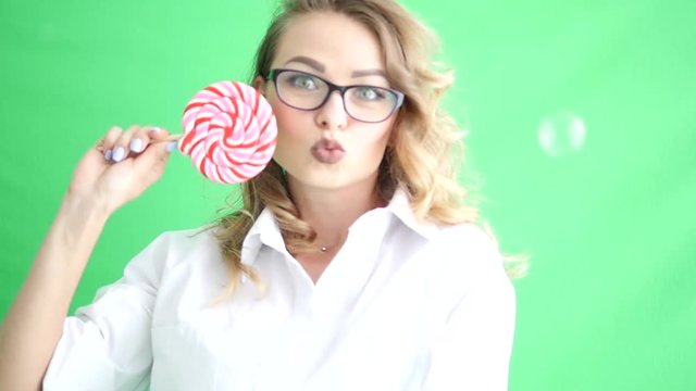 Cute funny girl old licking a big lollipop over green screen