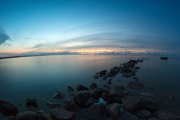 Long row of the stone breakwaters in the calm water of sea bay.