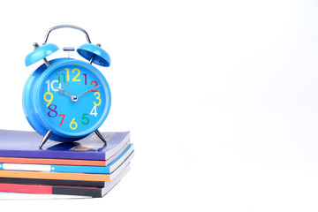 Concept Education or business :  Blue alarm clock is placed on a pile of books  isolated on white...